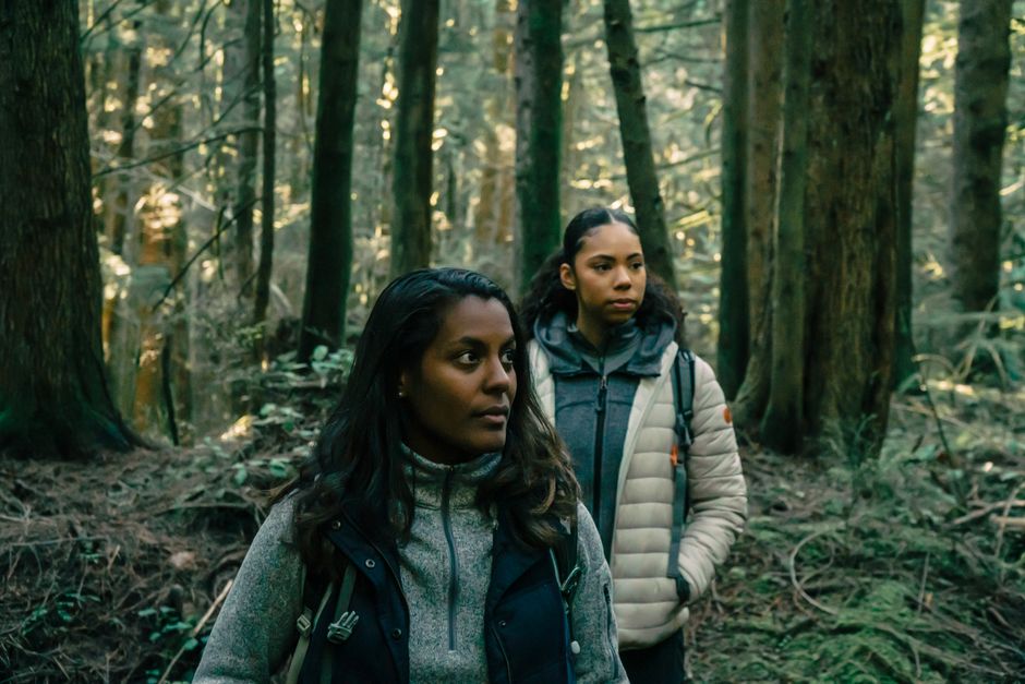 Two women hiking in a serene forest setting, embracing outdoor adventure.