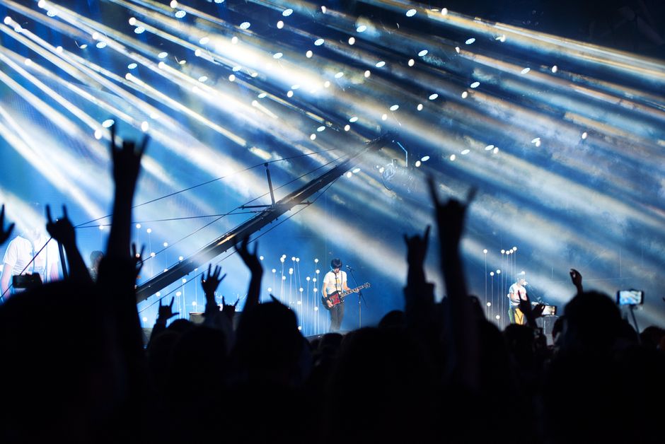Energetic live music performance with crowd cheering under dramatic lighting.