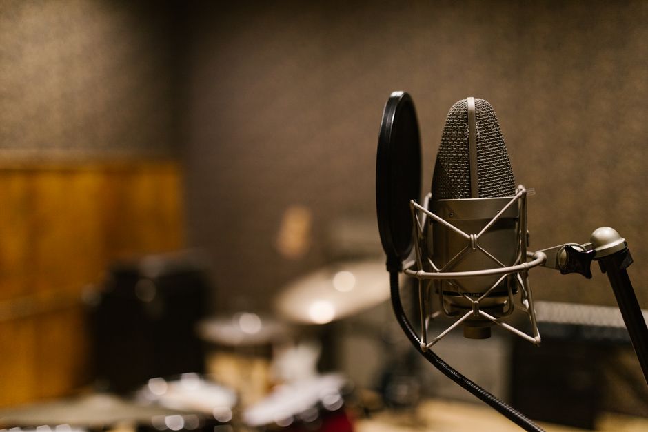 Close-up of a condenser microphone with a pop filter in a recording studio setting.