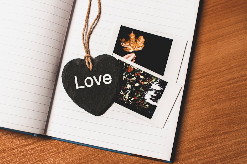 Heart-shaped chalkboard with 'Love' on an open notebook alongside photos. Perfect for Valentine's themes.