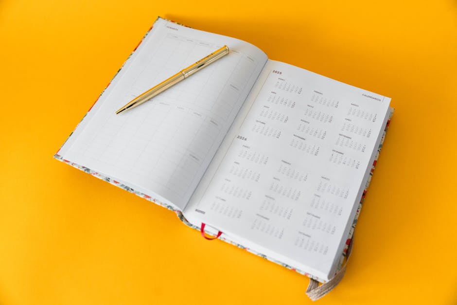 Open planner for 2023-2025 with a golden pen on a vibrant yellow background, perfect for organizing and planning.