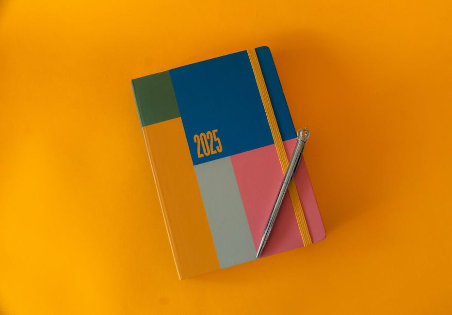 A vibrant 2025 planner with elegant pen on a bold yellow surface, perfect for organizing the year.