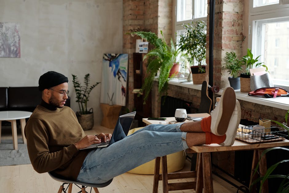 Young stylish man working on a laptop in a cozy urban apartment. Perfect setup for remote work.