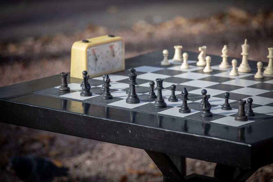 Detailed close-up of chessboard with pieces and timer outdoors, capturing strategy and focus.