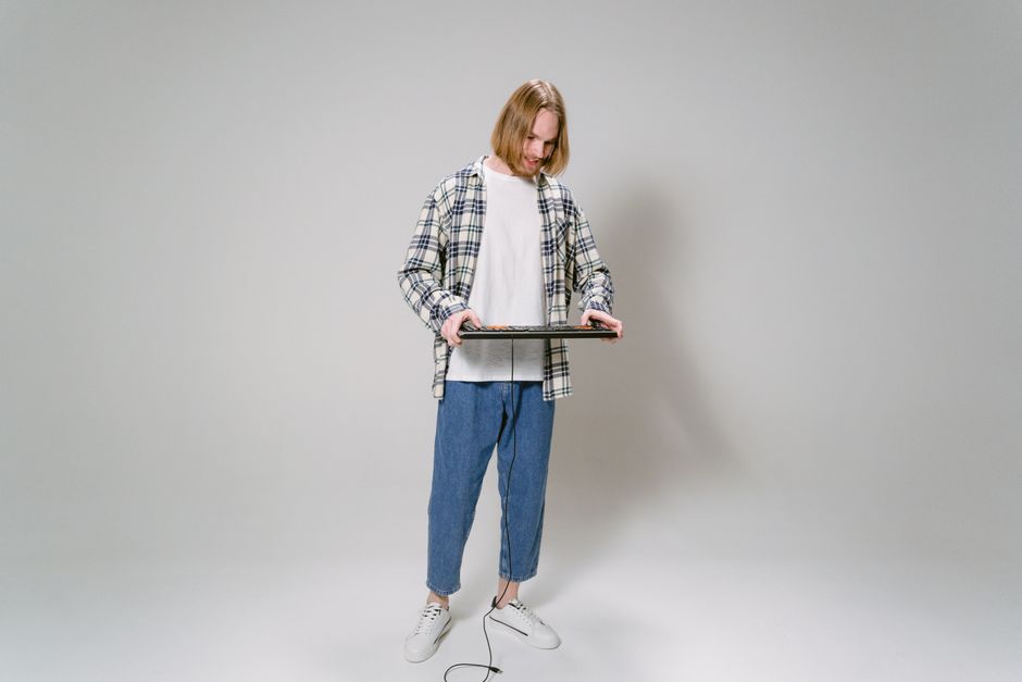 Young man in casual attire using a game console controller in a minimalist studio setting.