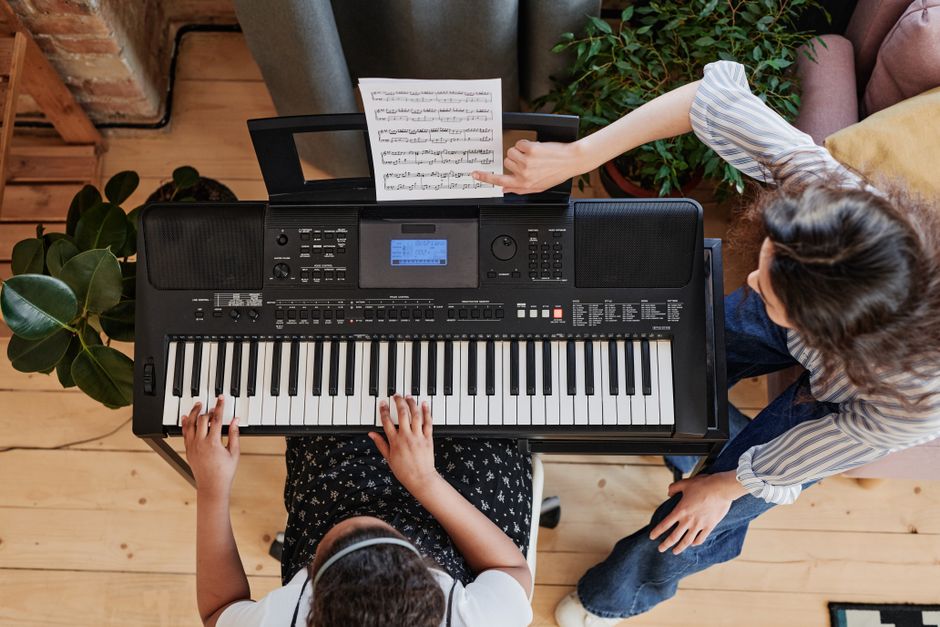 A child practicing piano under teacher guidance in a cozy indoor setting.
