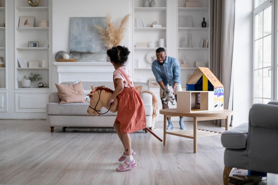 Father and daughter enjoying playful moment in stylish living room setting, highlighting family bonding.