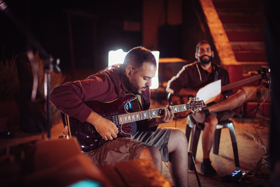 Two guitarists enjoying a jam session in an atmospheric indoor setting.