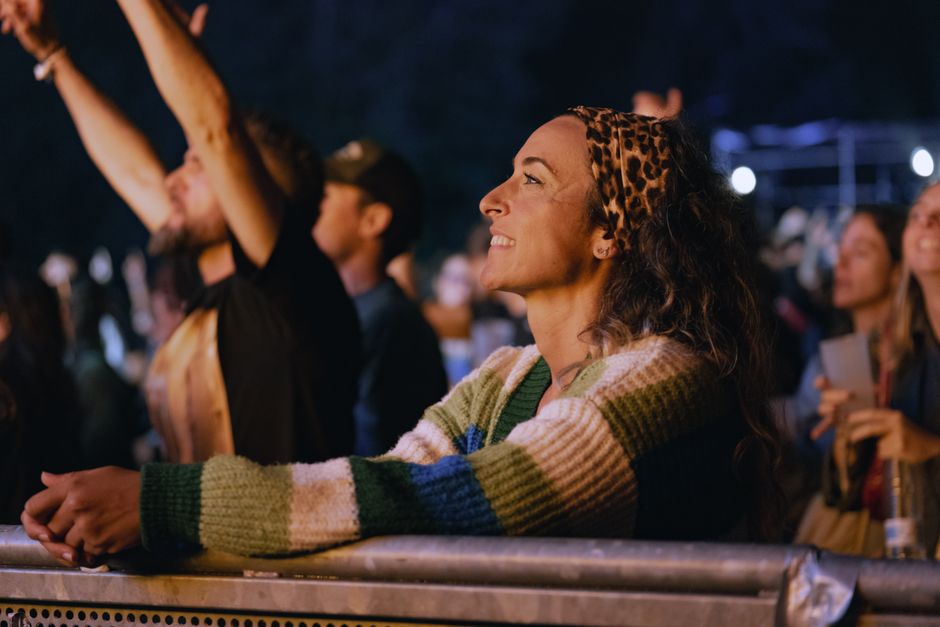 A lively crowd enjoys an outdoor night concert with positive energy.