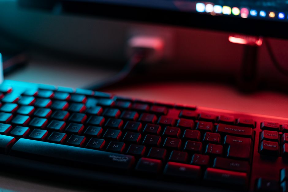A vibrant close-up view of a computer keyboard illuminated by red and blue light, emphasizing technology themes.