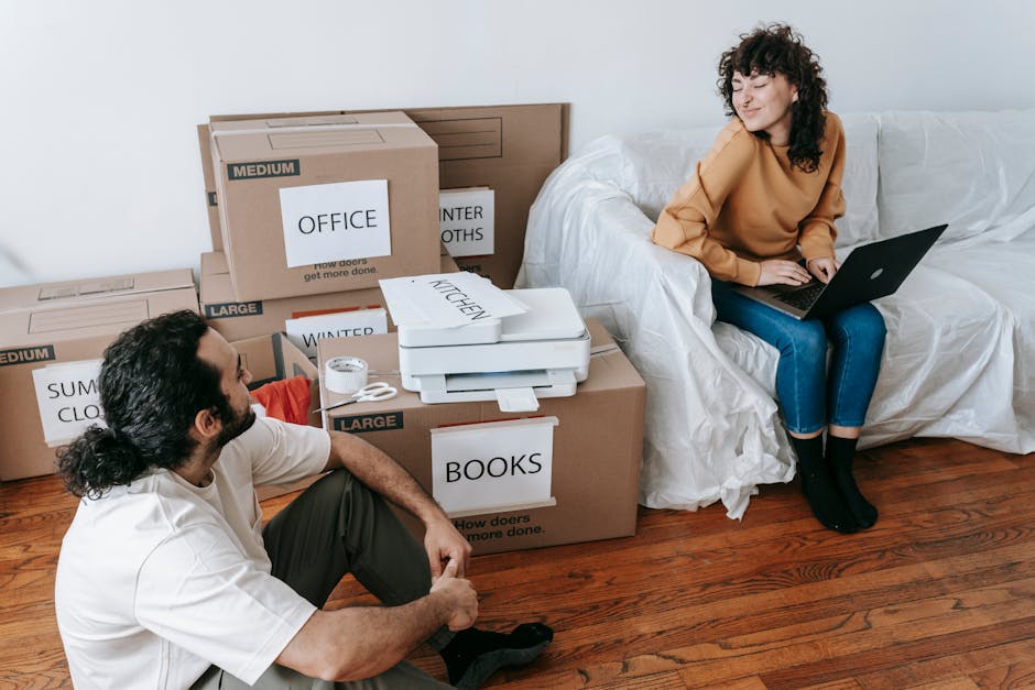 Young couple organizing boxes and relaxing with laptop during moving day indoors.