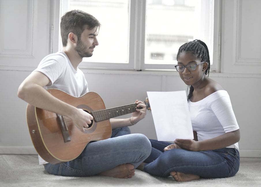 A couple enjoying music together, playing guitar and singing indoors. Intimate and relaxed atmosphere.
