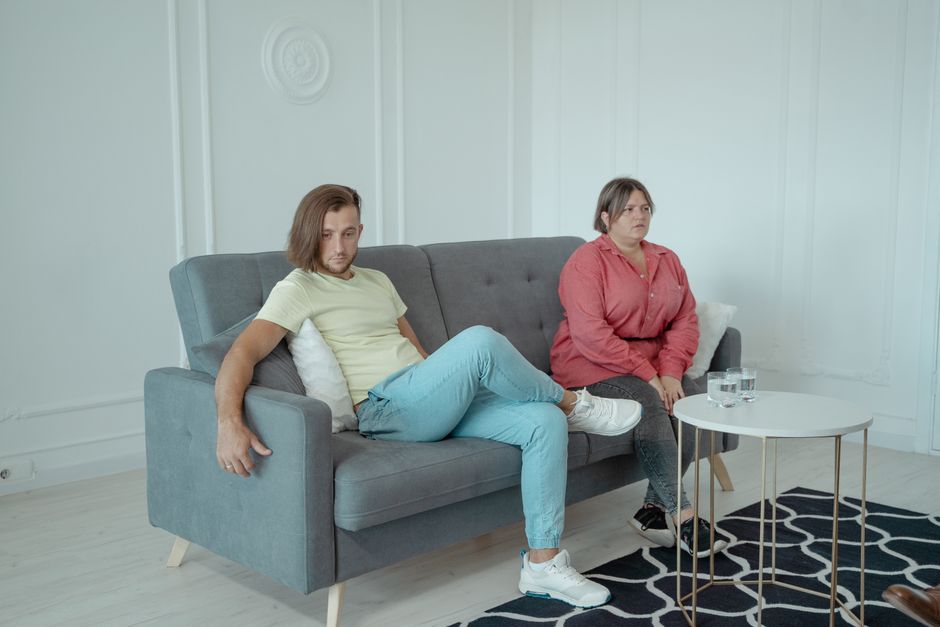 Couple in a therapy session sitting together on a modern sofa in a minimalist room.