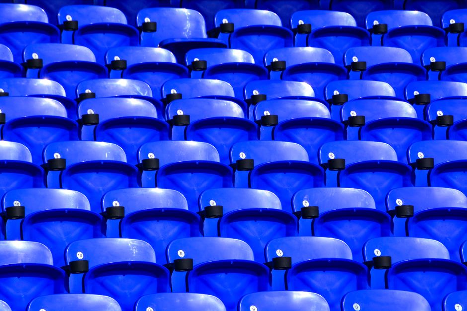 Rows of empty, vibrant blue stadium seats create a striking pattern.