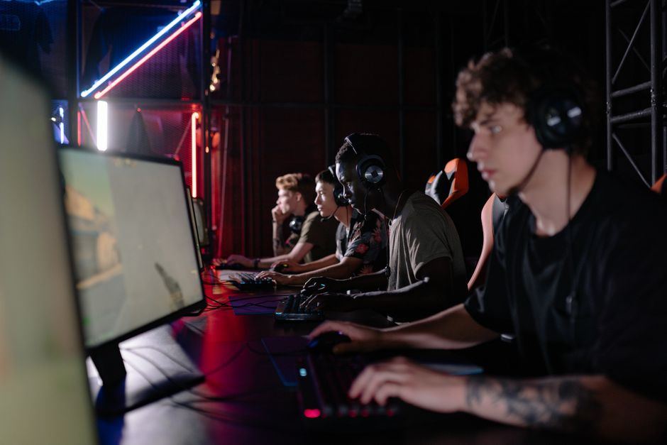Group of diverse gamers playing in an esports tournament with headsets and screens.