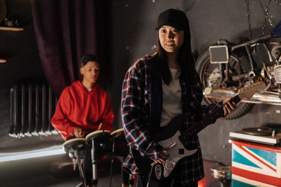 Two musicians play guitar and drums in a cozy garage setting, enjoying their music session.